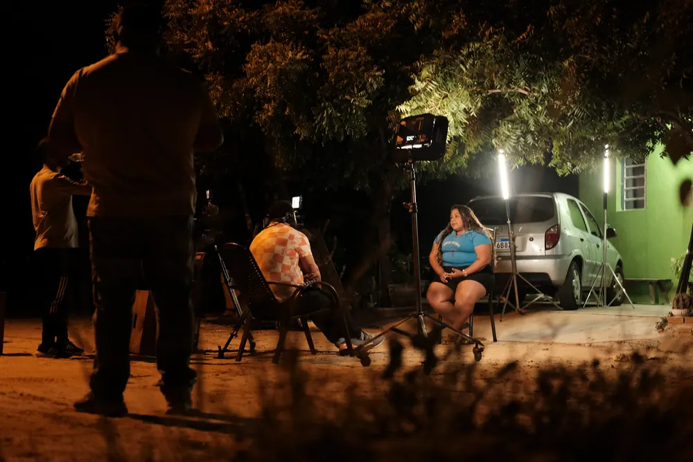 Entrevista noturna iluminada no terreiro.