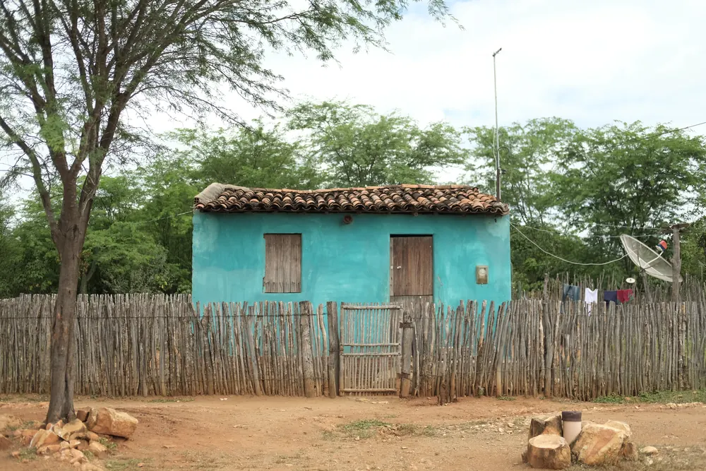 Casa azul cercada de varas na comunidade.